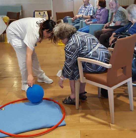 Une animatrice guide un exercice d'adresse avec ballon et cerceau lors d'une séance de gymnastique douce