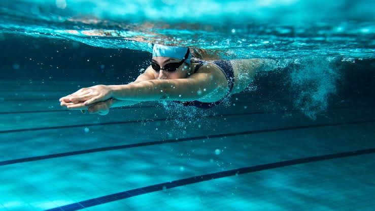 Une nageuse en crawl, vue sous la surface d'une piscine